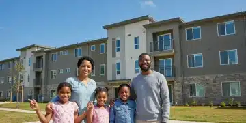 Family smiling in front of an affordable housing complex, symbolizing housing assistance programs and hope for stability.